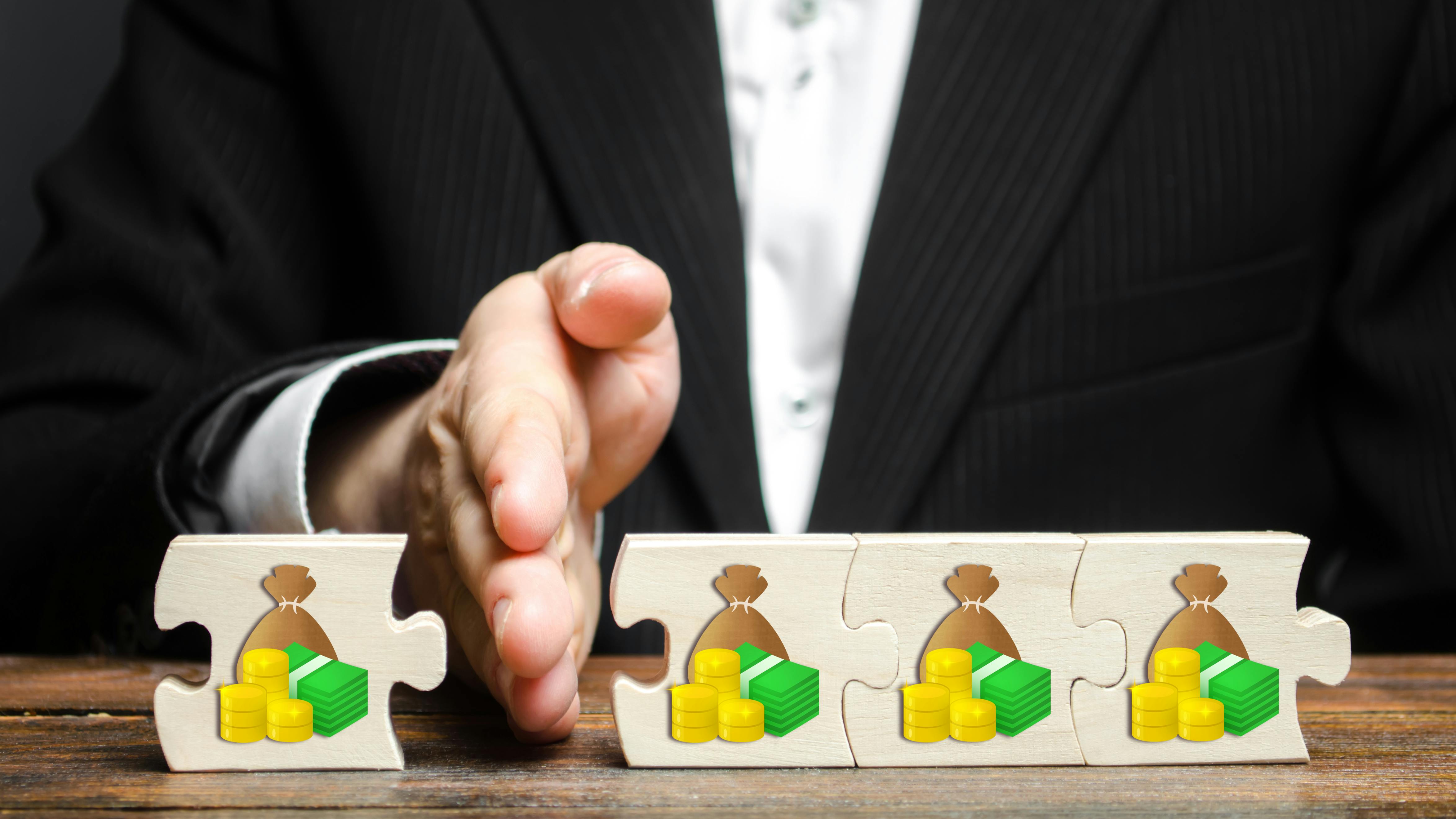 man's hand separating puzzle pieces of wealth