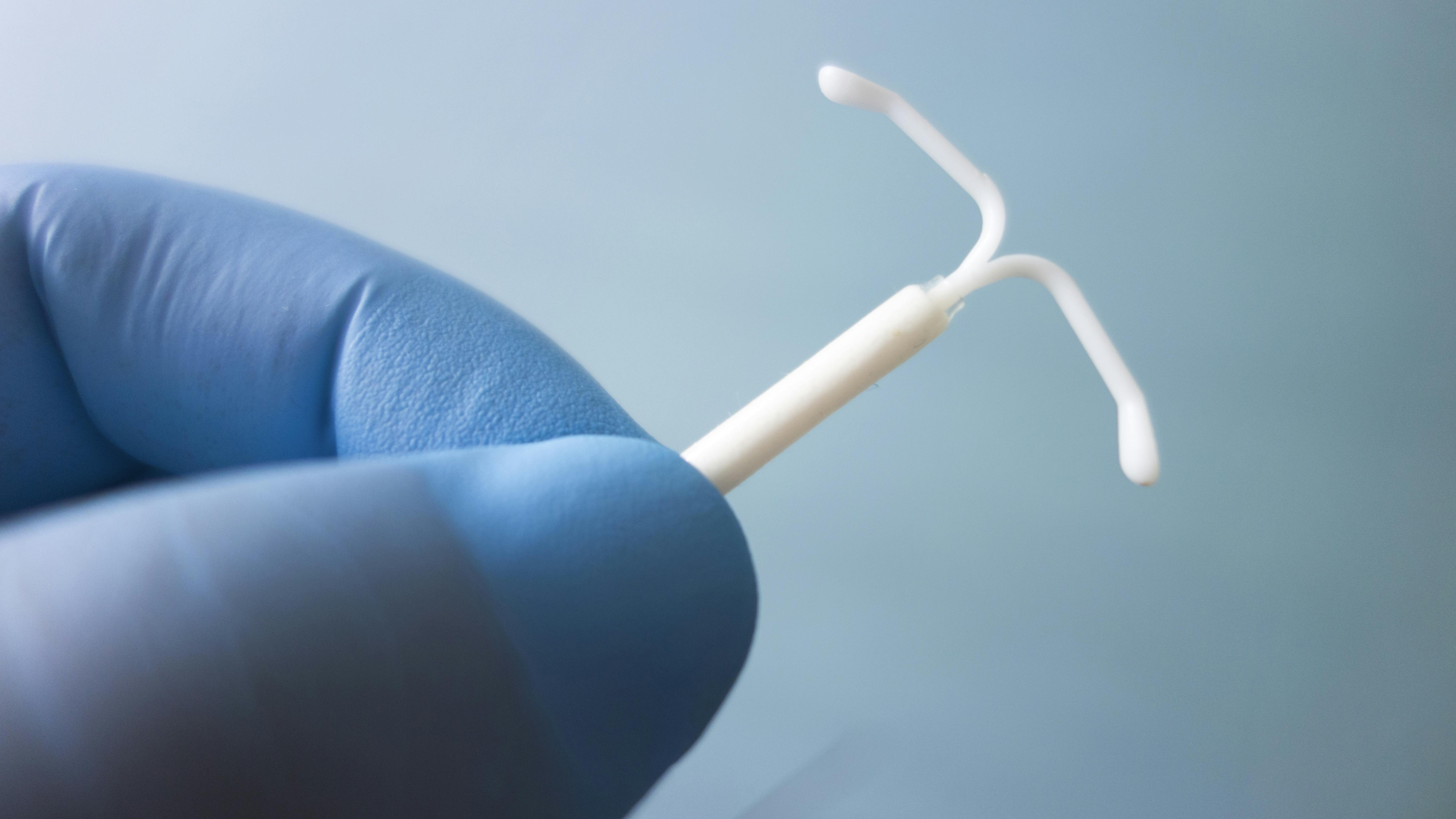 gloved hand holding an intrauterine device