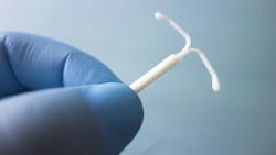 gloved hand holding an intrauterine device gloved hand holding an intrauterine device